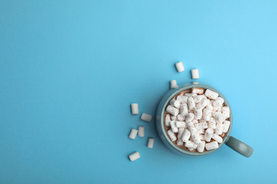 Photo of Delicious cocoa drink with marshmallows on light blue background, top view. Space for text