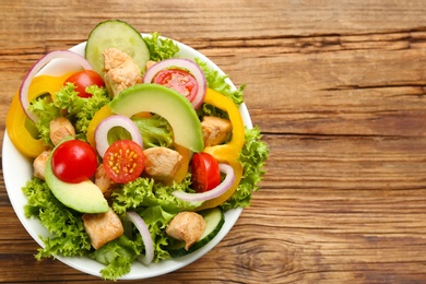 Photo of Delicious fresh chicken salad served on wooden table, top view. Space for text