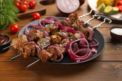 Photo of Metal skewers with delicious meat and onion served on wooden table