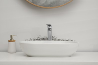 Image of White wall affected with mold. White washbasin and soap dispenser in bathroom