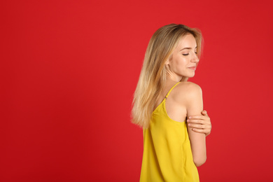 Photo of Beautiful young woman with blonde hair on red background. Space for text