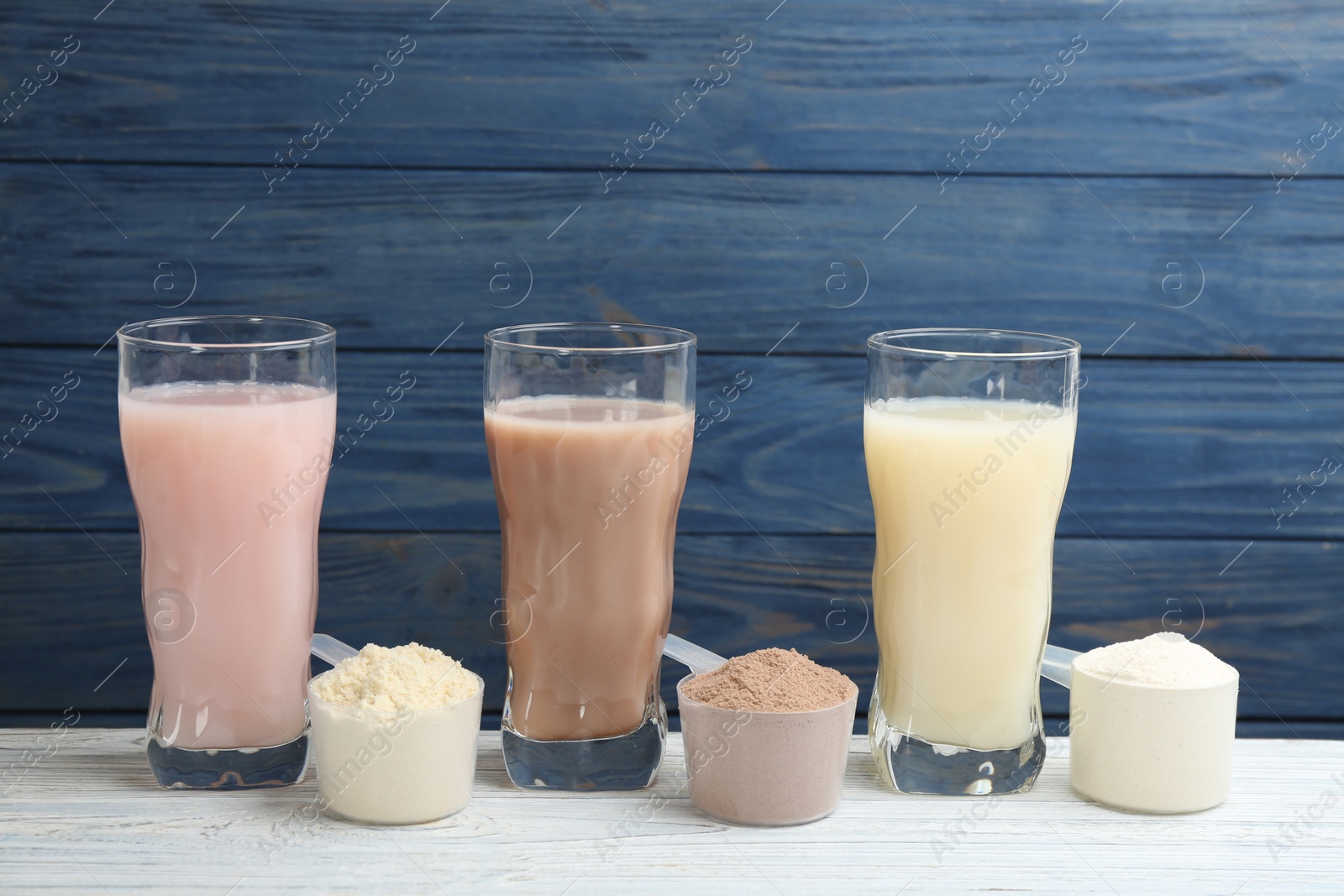 Photo of Protein shakes and powder on white wooden table