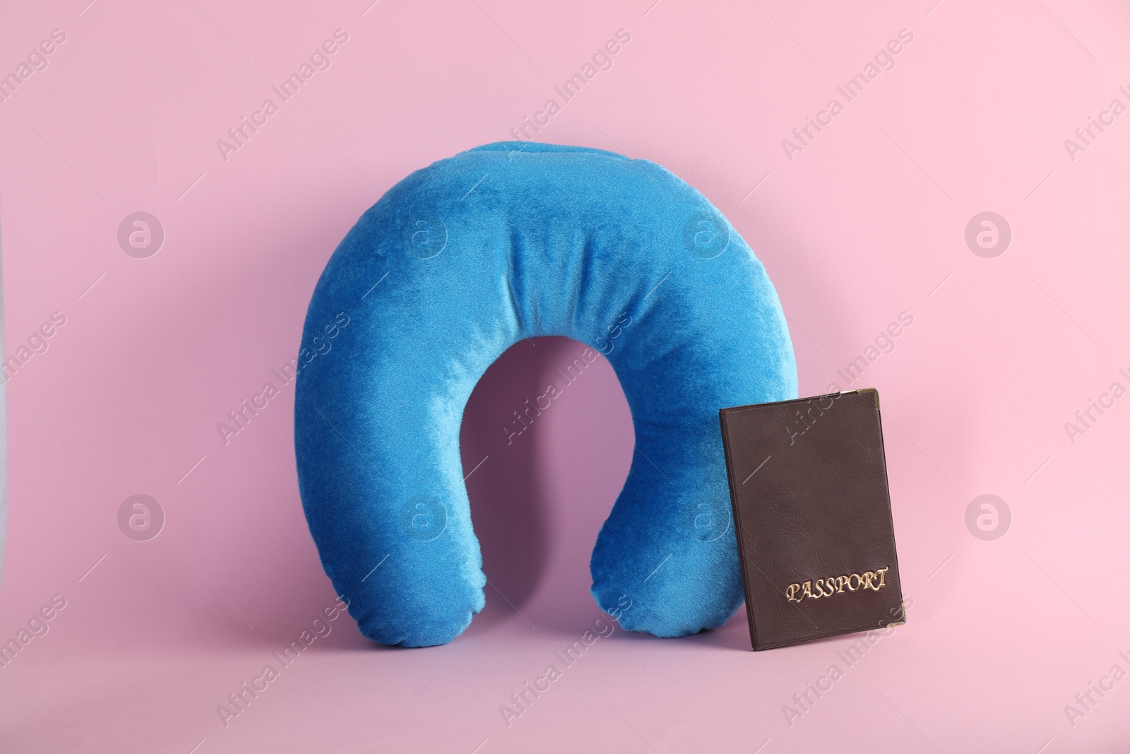 Photo of Light blue travel pillow and passport on pink background