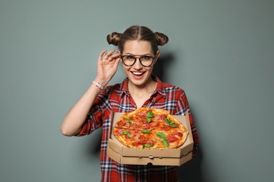 Attractive young woman with delicious pizza on color background