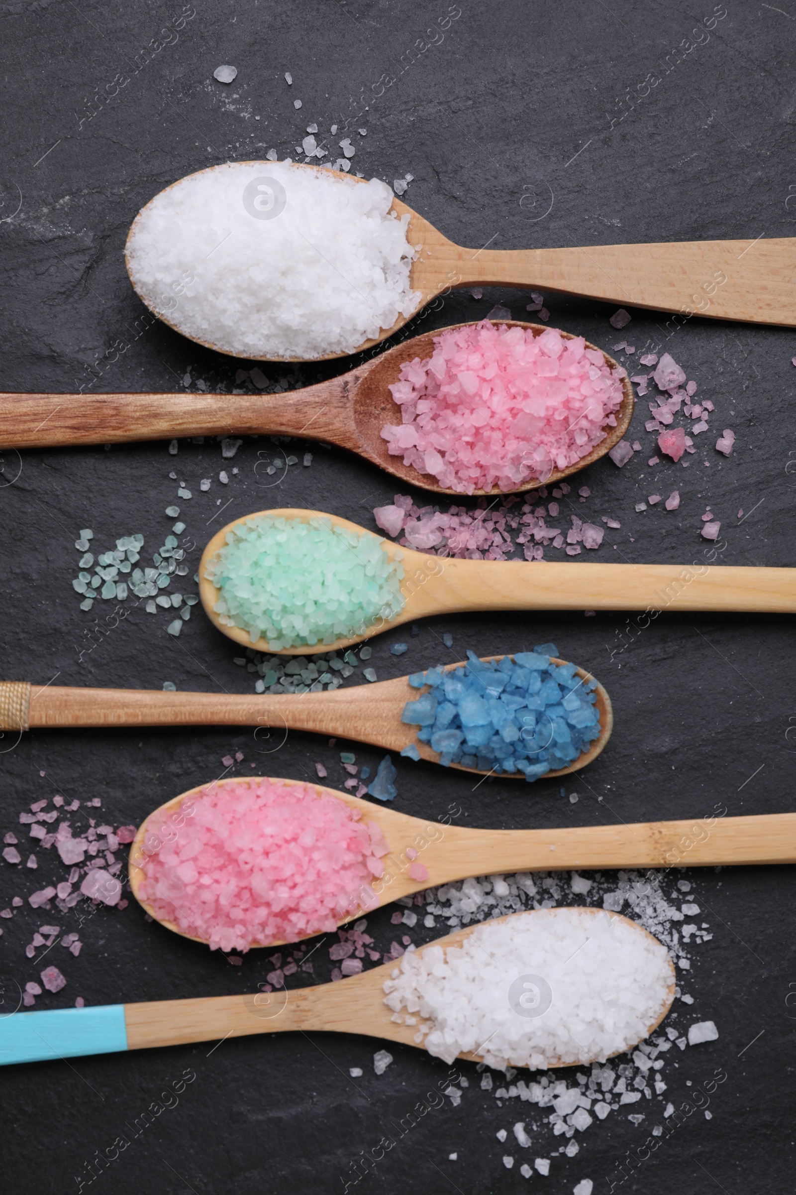 Photo of Spoons with different sea salts on black table, flat lay