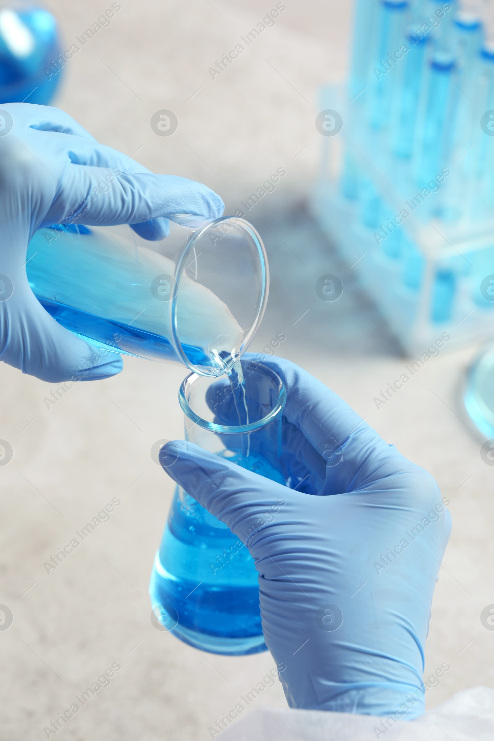 Photo of Scientist working with beakers at grey table, closeup