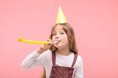 Photo of Cute little girl in party hat with blower on pink background