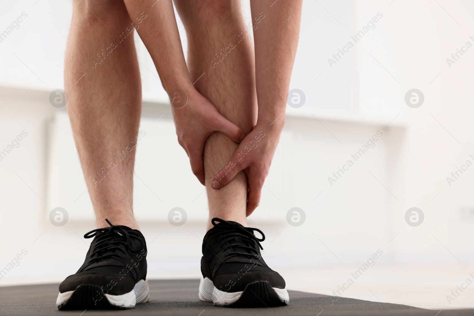 Photo of Man suffering from leg pain on mat indoors, closeup. Space for text