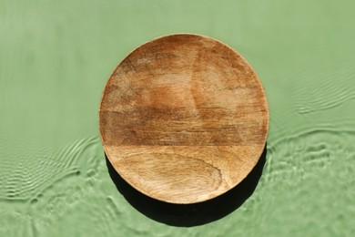 Photo of Presentation for product. Wooden podium in water on green background, top view