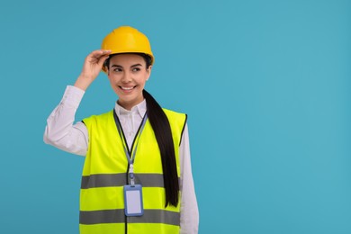 Photo of Engineer with hard hat and badge on light blue background, space for text