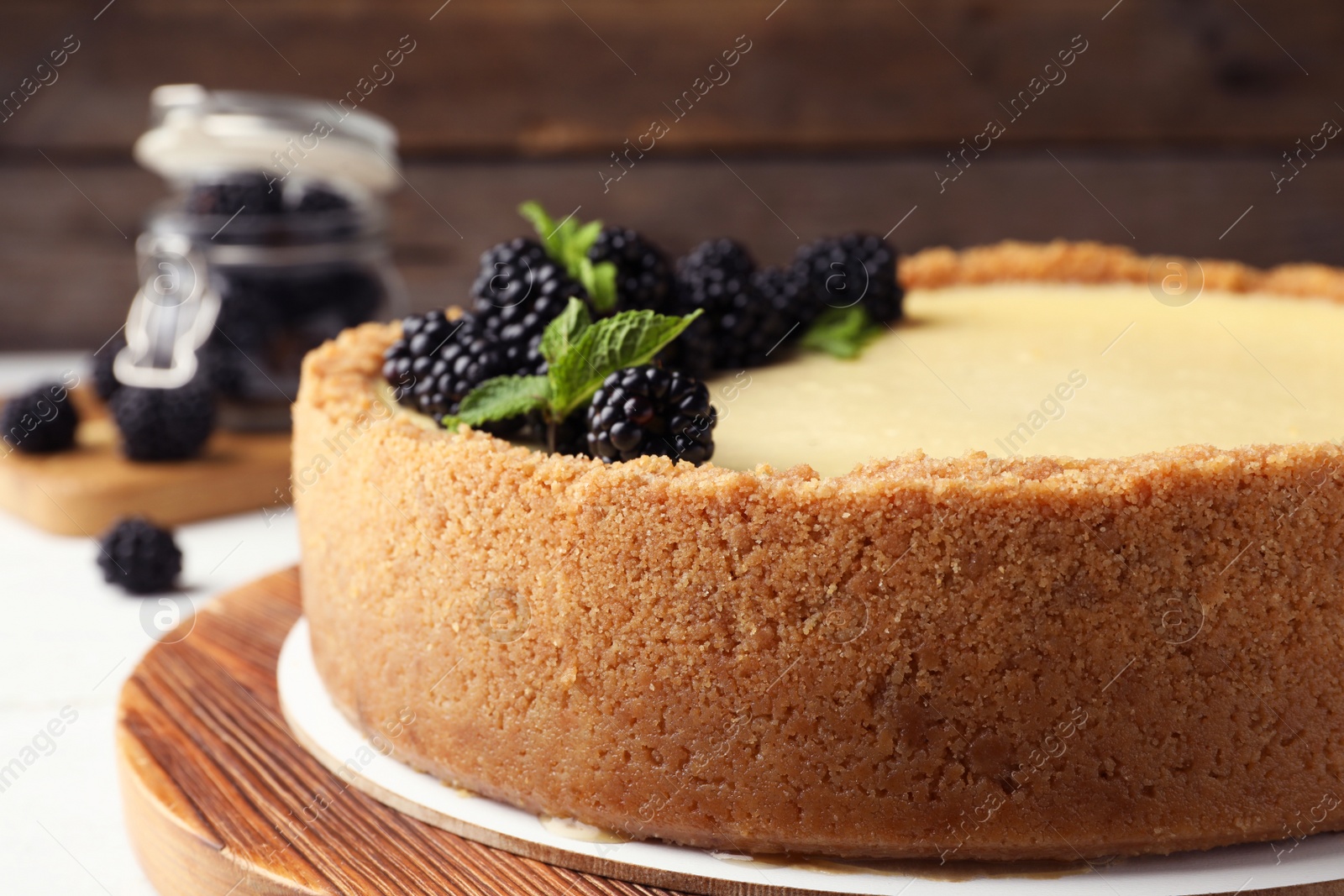 Photo of Delicious cheesecake decorated with blackberries on table