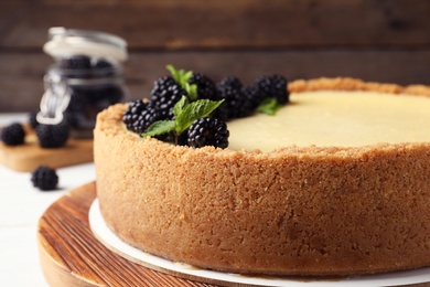 Photo of Delicious cheesecake decorated with blackberries on table