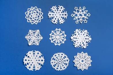 Many paper snowflakes on blue background, flat lay