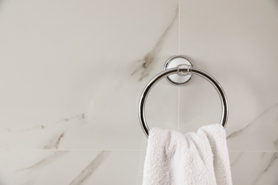 Photo of Holder with clean towel on light wall. Space for text