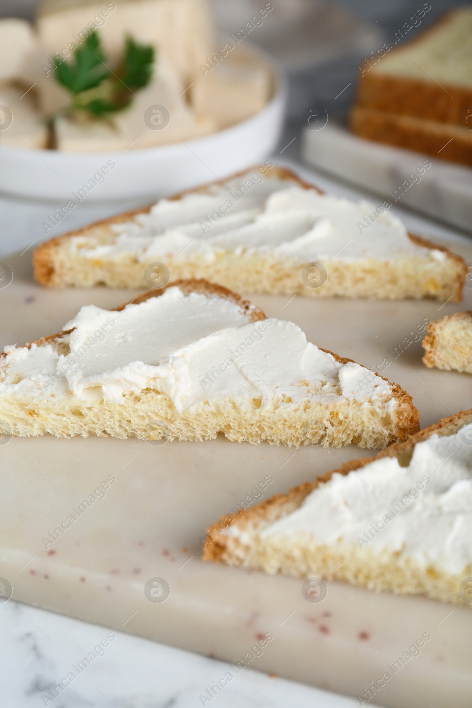 Photo of Delicious toasts with tofu cream cheese on white marble table, closeup