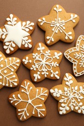 Photo of Tasty Christmas cookies with icing on brown background, flat lay