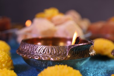 Photo of Diwali celebration. Diya lamp on shiny light blue table, closeup