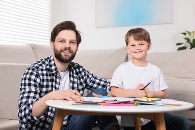 Family portrait of happy dad and son at coffee table indoors
