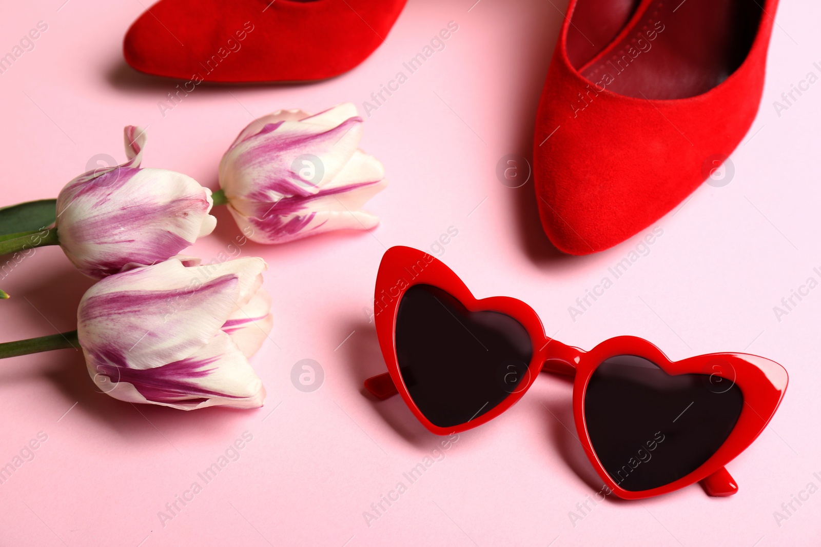 Photo of Heart shaped sunglasses, shoes and tulip flowers on color background