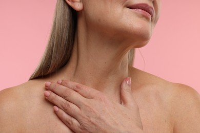 Mature woman with healthy skin on pink background, closeup