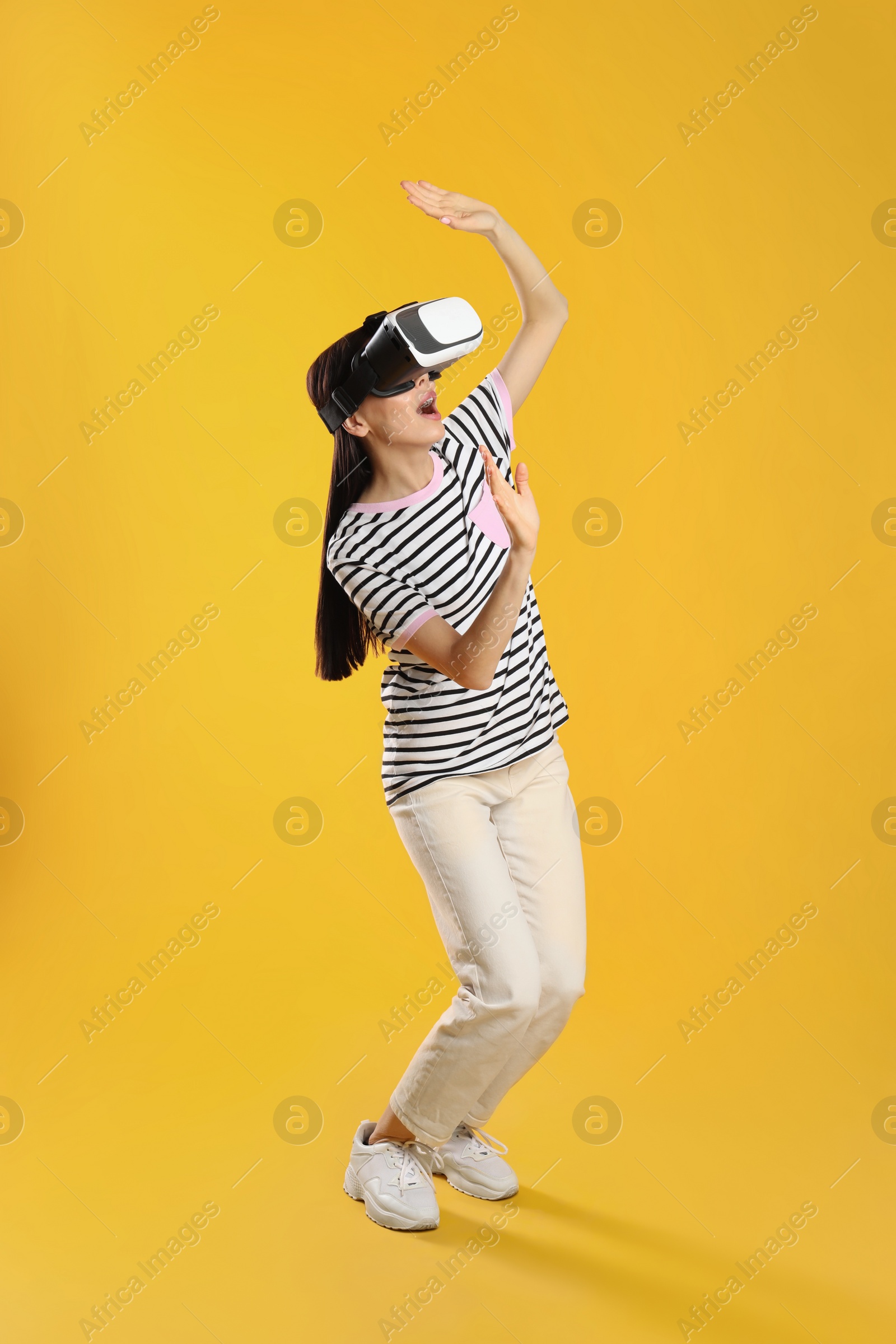 Photo of Woman using virtual reality headset on yellow background