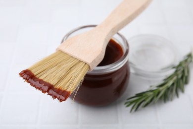 Photo of Marinade in jar and basting brush on white table, closeup