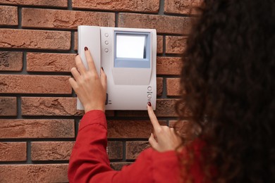 Photo of African-American woman pressing button on intercom panel indoors