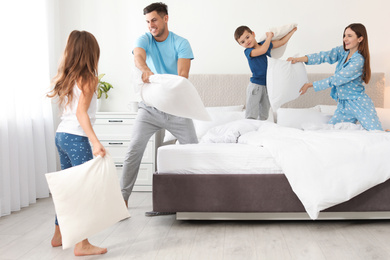 Photo of Happy family having pillow fight in bedroom