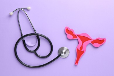 Reproductive medicine. Paper uterus and stethoscope on violet background, top view