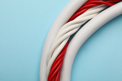 Photo of Many electrical cables on light blue background, closeup