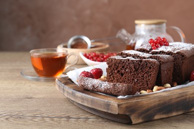 Photo of Tasty chocolate sponge cake with nuts and berries on wooden table, closeup. Space for text