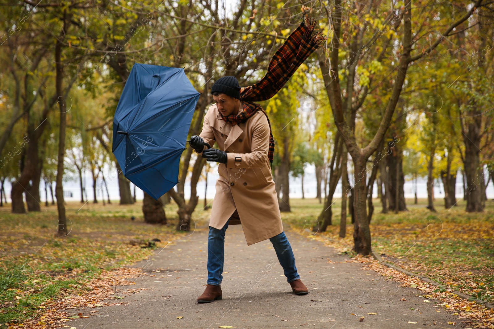 Photo of Man with blue umbrella caught in gust of wind outdoors