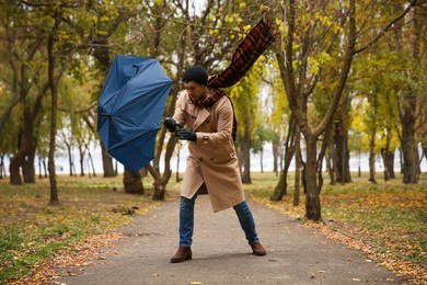 Man with blue umbrella caught in gust of wind outdoors