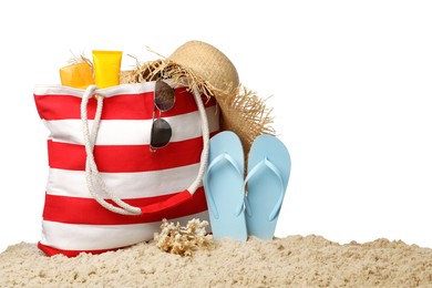 Stylish bag with beach accessories on sand against white background