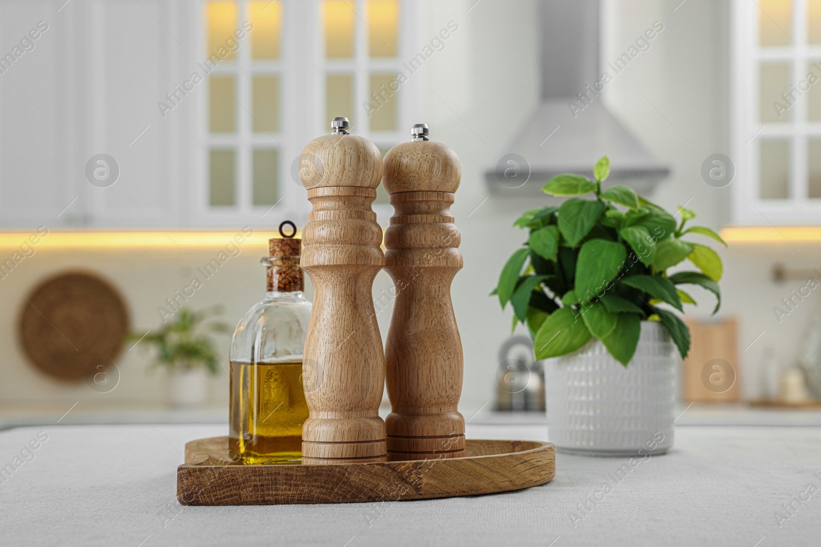 Photo of Wooden salt and pepper shakers, bottle of oil on white table in kitchen