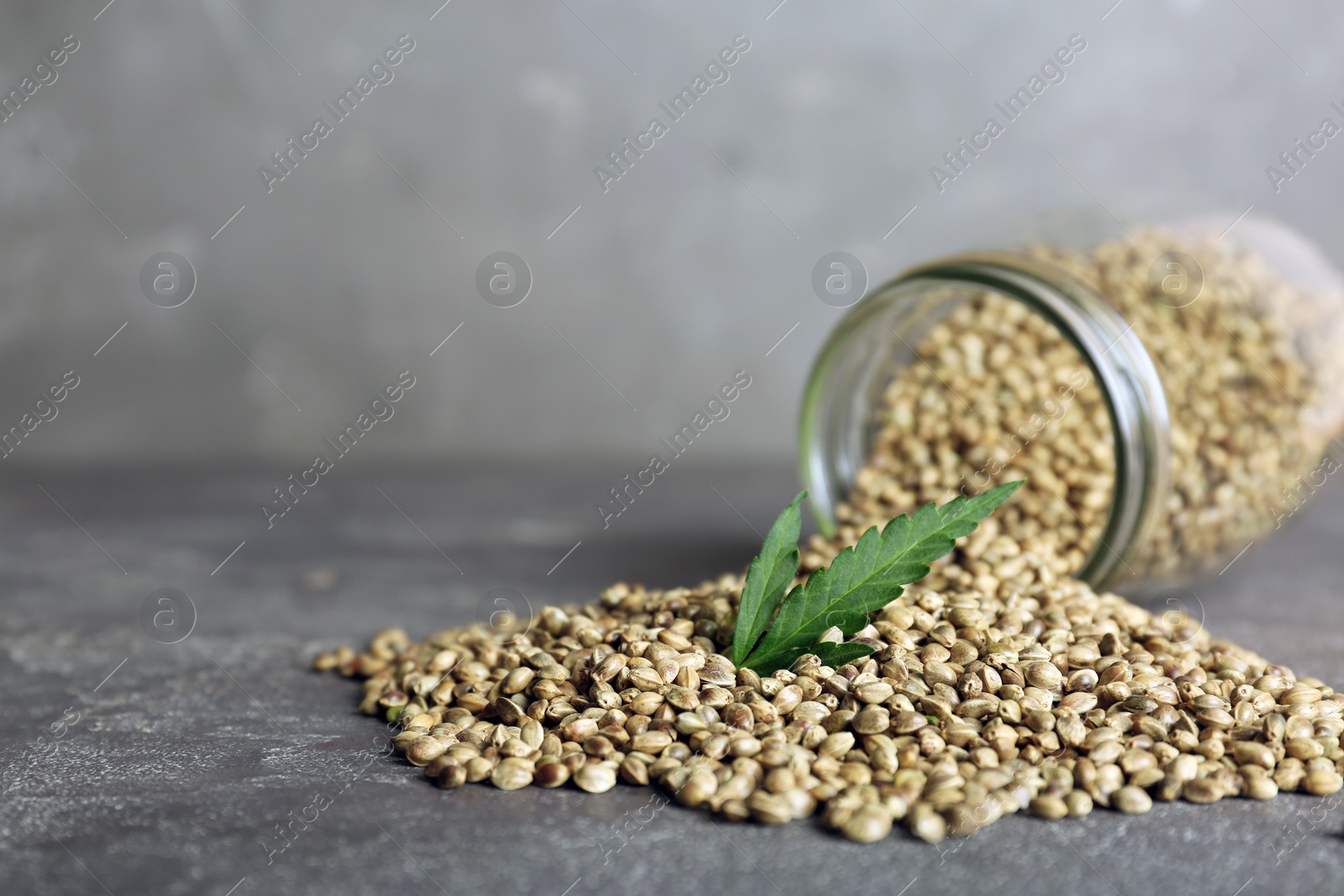 Photo of Overturned jar with hemp seeds on table