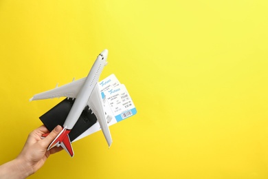 Photo of Woman holding toy airplane, passport and tickets on yellow background, closeup. Space for text