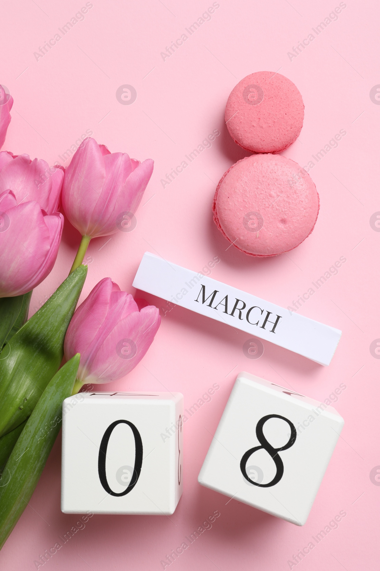 Photo of International Women's day - 8th of March. Macaron cookies, wooden block calendar and beautiful flowers on pink background, flat lay