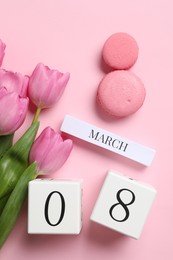 International Women's day - 8th of March. Macaron cookies, wooden block calendar and beautiful flowers on pink background, flat lay