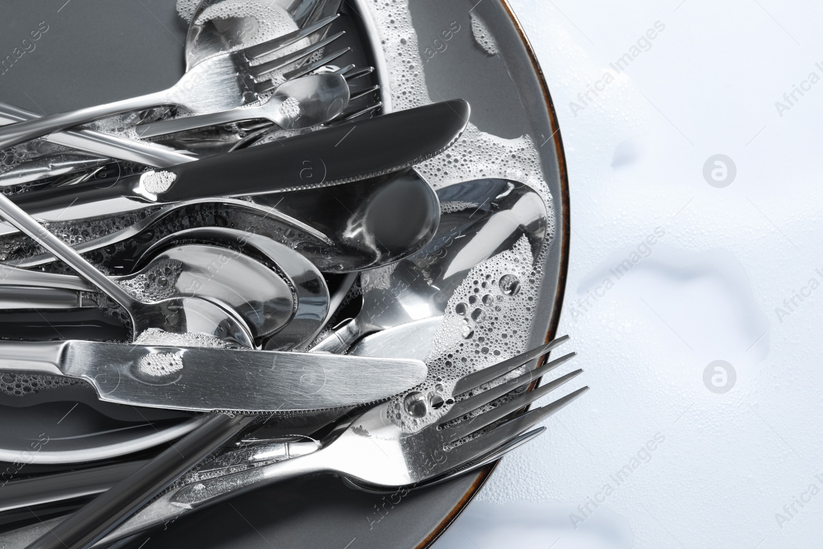 Photo of Plate with silverware in foam, above view. Space for text