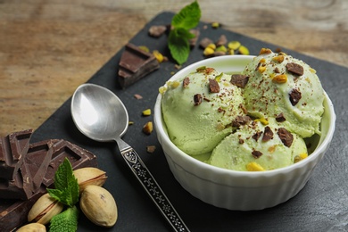 Photo of Delicious green ice cream served in ceramic bowl on wooden table