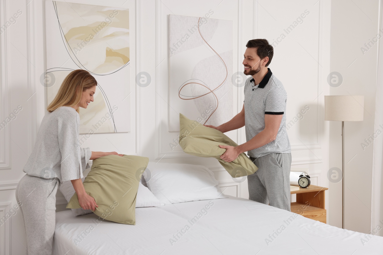 Photo of Couple changing bed linens at home. Domestic chores