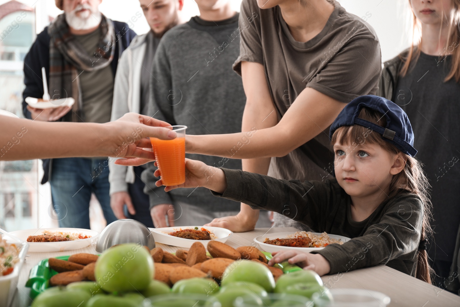 Photo of Poor people receiving food from volunteers indoors