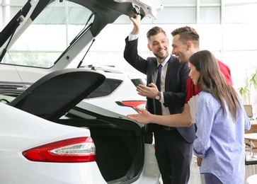 Young couple buying new car in salon