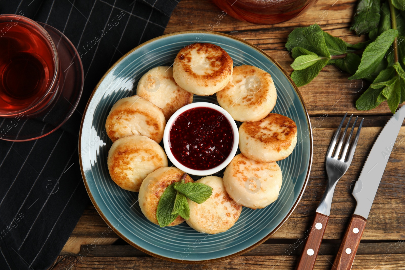 Photo of Delicious cottage cheese pancakes with jam and mint on wooden table, flat lay