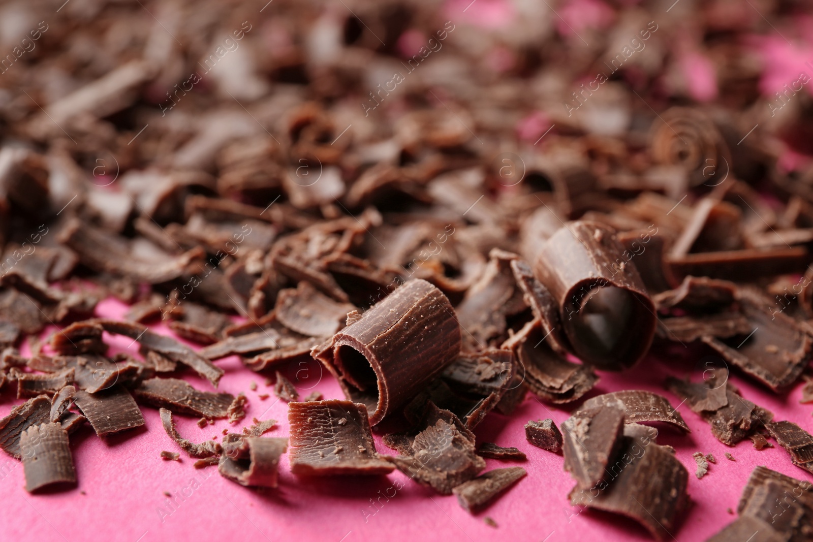 Photo of Curls of tasty chocolate on color background, closeup