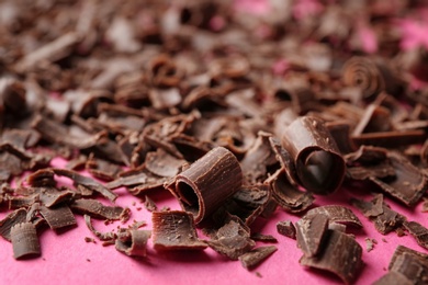 Curls of tasty chocolate on color background, closeup