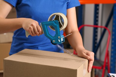 Post office worker packing parcel indoors, closeup