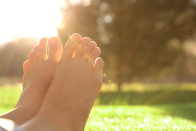 Young woman sitting barefoot outdoors, closeup view