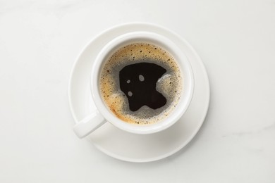 Cup of aromatic coffee on white table, top view